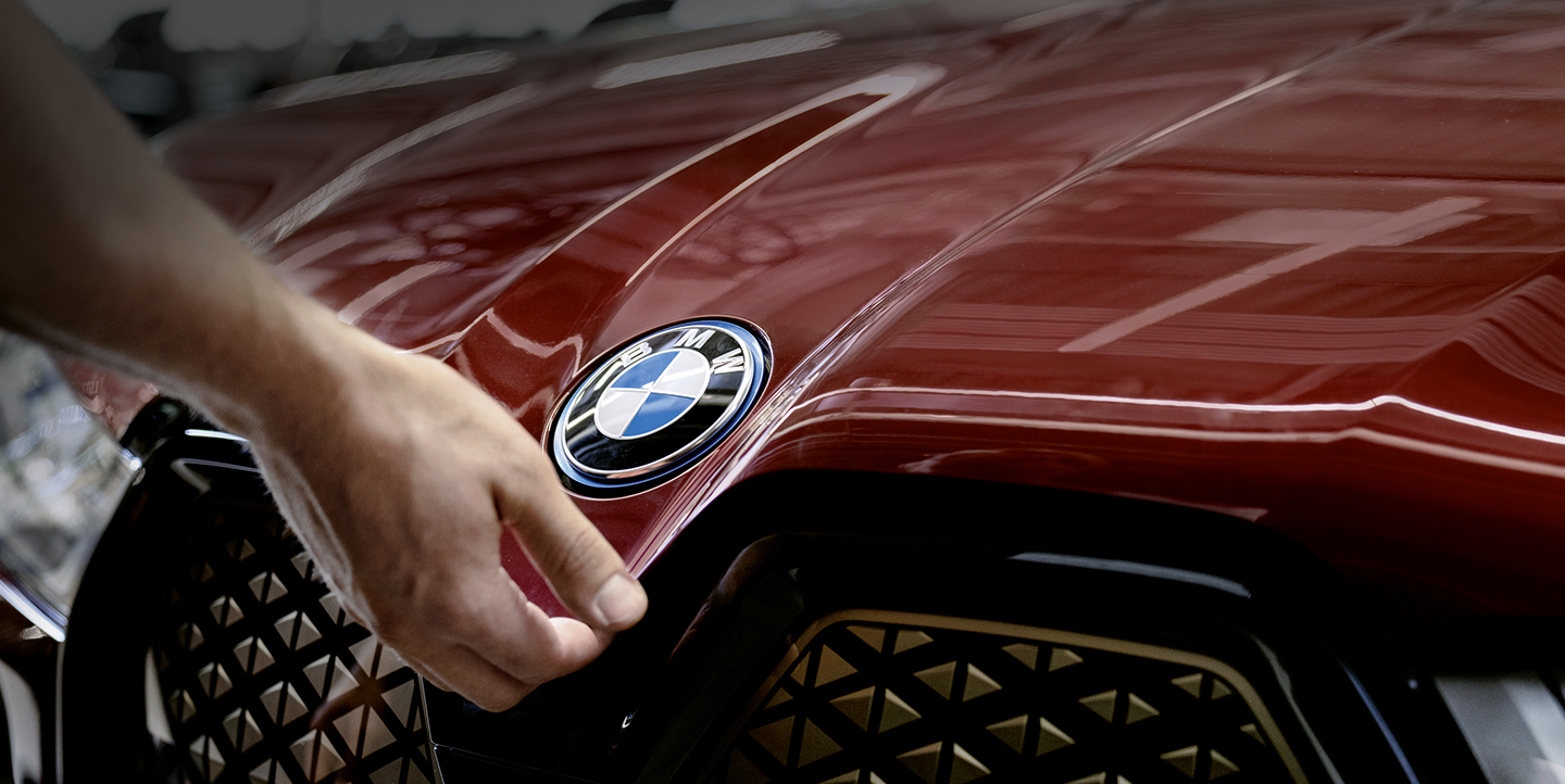 Nahaufname einer Hand die die Motorhaube eines roten BMW öffnet